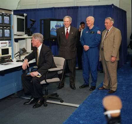 Clinton and Glenn At Houston s Johnson Space Center, United States President Bill Clinton looks at a monitor while communicating long distance with the STS-90 crew preparing for a launch in two days at the Kennedy Space Center in Florida on April 14, 1998. Others pictured, in near background, are (from the left) NASA Administrator Daniel Goldin, U.S. Senator John H. Glenn Jr. (Democrat of Ohio) and JSC Director George W.S. Abbey. Clinton addressed the importance of the the Neurolab mission and asked the crew commander--astronaut Richard A. Searfoss--to profile the mission s objectives for the press corps accompanying the president on his JSC visit. Glenn is at JSC in preparation to fly as a payload specialist on the STS-95 mission later thi Copyright: xx S98-05016 NASAx cnpphotos032496