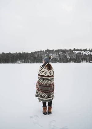 Woman wrapped in blanket on shore of frozen lake on winter day. Kingston, Ontario, Canada R_DOHO240204D-1345071-01 ,model released, Symbolfoto