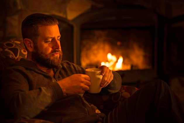 Man (40) sitting by a warm open fire at a log cabin ski chalet in Mont Tremblant, Quebec, Canada ER20170409-Stock-00123  Copyright: x xAllxCanadaxPhotosx 1990-13859206 ,model released, Symbolfoto