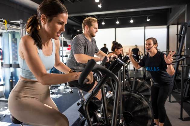 Energetic fitness instructor encouraging class while they exercise on bicycle machines Dallas Texas USA  Copyright: xStewartxCohenxPicturesx 4009-18760475 ,model released, Symbolfoto ,property released