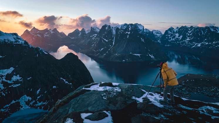 Man photographing through camera on mountain in winter at sunrise Reine, Nordland, Norway CR_BRHU240206-1329251-01 ,model released, Symbolfoto
