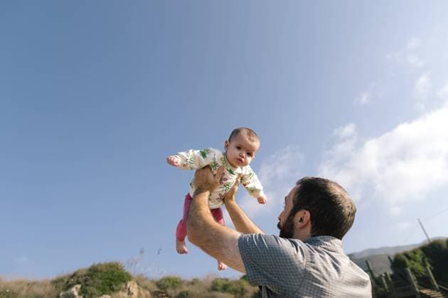 Creative Highlights Symbolbilder Baby Reacts Mildly To Being Held Up High By Father While Outside Malibu, California, United States CR_ANWHER240207-1349180-01 ,model released, Symbolfoto