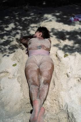Creative Highlights Symbolbilder A woman with a short haircut lies on the sand on the beach. Lembongan, Bali, Indonesia R_YUKI240208C-1331382-01 ,model released, Symbolfoto ,property released