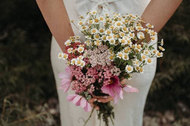 Woman in a white dress holding a bunch of wild flowers in her hands Thun, Canton of Bern, Switzerland R_FFVO240213D-1353960-01