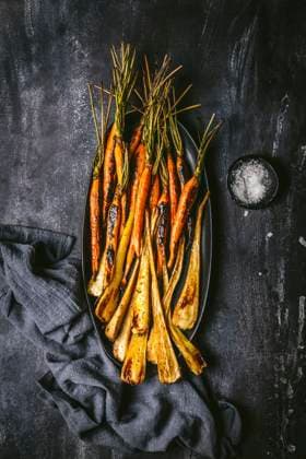 Roasted, glazed carrots and parsnips arranged on a dark oval platter with gray linen napkin on dark background Roasted, glazed carrots and parsnips arranged on a dark oval platter with gray linen napkin on dark background Copyright: xEmilyxCliftonx EC200923-20