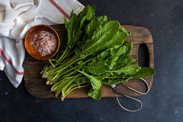 IMAGO Creative, Food, Trend, Meal Prep Top view of bunch of fresh arugula leaves alongside a bowl of pink salt and scissors on a rustic wooden cutting board, set against a dark tabletop with a striped towel Model Released AnnaBogush_ID18975_564904_007 Copyright: xAnnaxBogushx