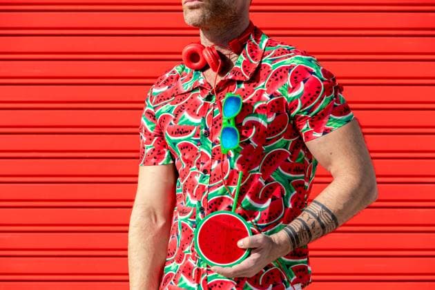 Crop unrecognizable male looking away while standing wearing printed water melon slices shirt and carrying mock juice with straw in hand against red background Model Released SergioVictorVega_ID19622_581836_001 Copyright: xSergioxVictorxVegax RECORD DATE NOT STATED