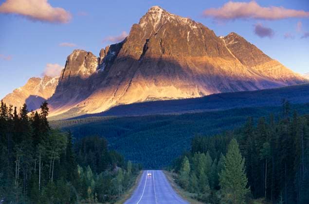 Mount Fitzwilliam looms over a lone vehicle on the Yellowhead Highway at dawn, Mount Robson Provincial Park, British Columbia, Canada.  Copyright: x AllCanadaPhotos.comx 1990-52396