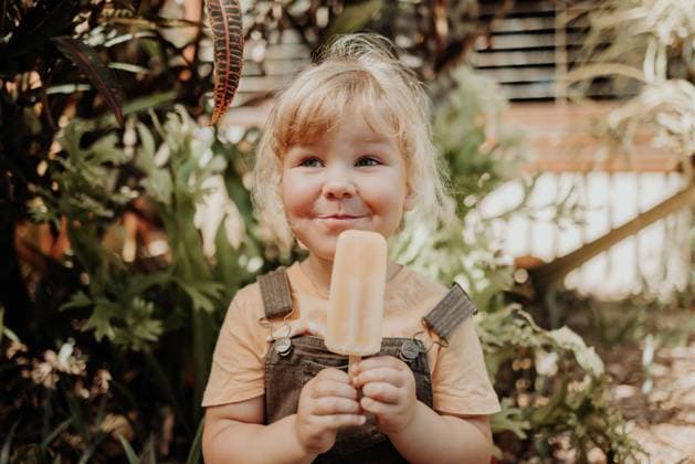 Creative Highlights Symbolbilder Young girl grins happily with icy pole or ice cream Woodgate, Queensland, Australia CR_OELC240214-1353578-01 ,model released, Symbolfoto