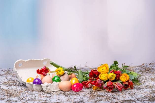 Bunte Ostereier auf einem Tisch mit Bumenstrauß als Postkartenmotiv zu Ostern *** Colorful Easter eggs on a table with a bouquet of flowers as a postcard motif for Easter