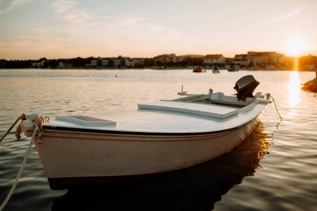 Small boat on calm water, moored in the harbor during sunset. A small boat on calm water, moored in the harbor, dock during sunset. model released
