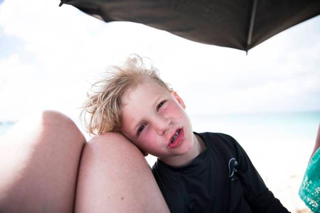 Creative Highlights Symbolbilder Young Blonde Boy Rests Head Against Mom s Knees at Beach East End Village, Anguilla CR_EMJA240225-109008-01 ,model released, Symbolfoto