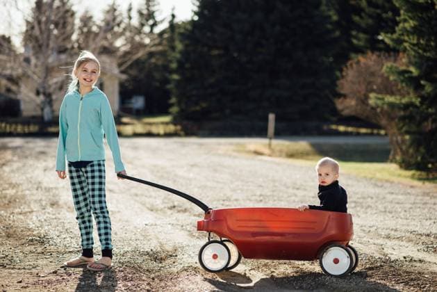 Full view of preteen girl smiling while pulling boy in toy wagon United States, North Dakota, Bismarck CR_KIFR240225-1356982-01 ,model released, Symbolfoto