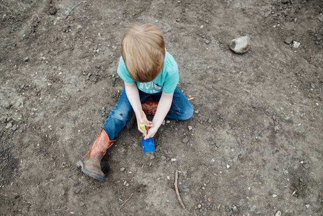 Creative Highlights Symbolbilder Overhead view of young boy sitting in dirt using a small shovel United States, North Dakota, Bismarck CR_KIFR240225-1356995-01 ,model released, Symbolfoto