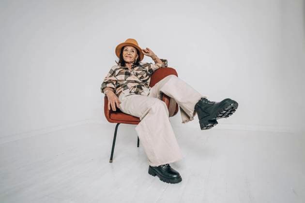 Creative Highlights Symbolbilder Carefree senior woman sitting on chair in front of white wall model released, Symbolfoto, ADF00279