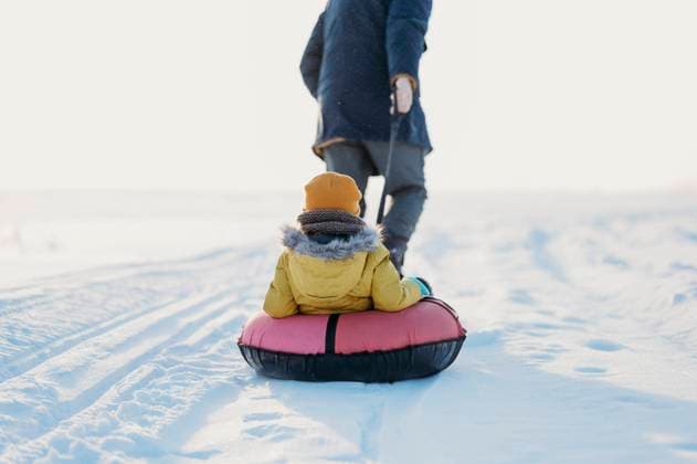 Creative Highlights Symbolbilder Father pulling son siting on inflatable tube in winter model released, Symbolfoto, ANAF02680