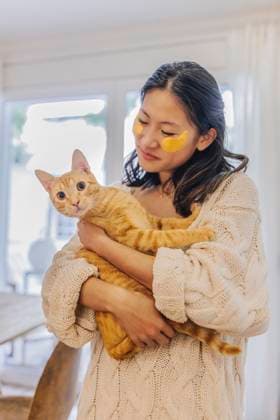 Smiling woman with under eye patches holding cat at home model released, Symbolfoto property released, ASNF00027