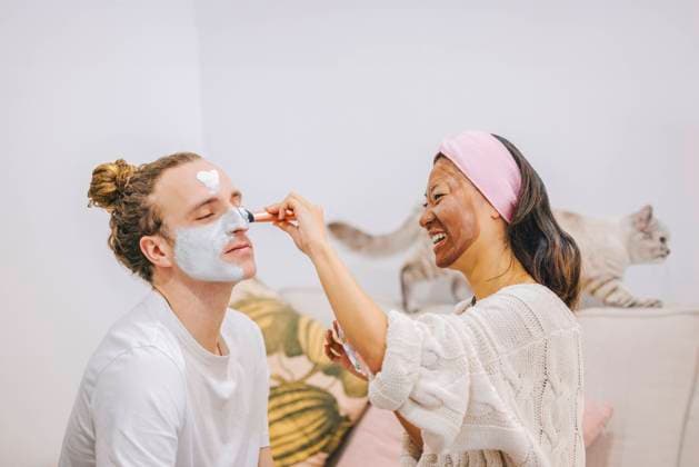 Happy woman applying skincare mask on boyfriend s face at home model released, Symbolfoto property released, ASNF00031