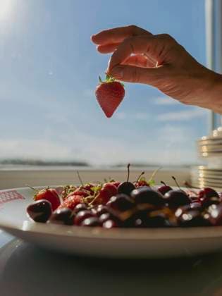 Hand of woman holding strawberry near window at home model released, Symbolfoto, IEF00532