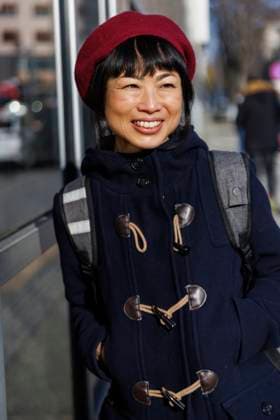 Happy mature woman standing with backpack near glass window on sunny day model released, Symbolfoto, IKF01721