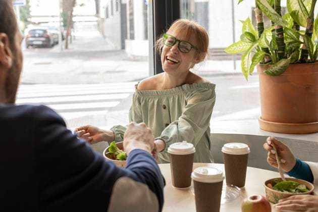 Cheerful businesswoman sharing lunch with colleague in cafeteria at workplace model released, Symbolfoto property released, JCCMF11199