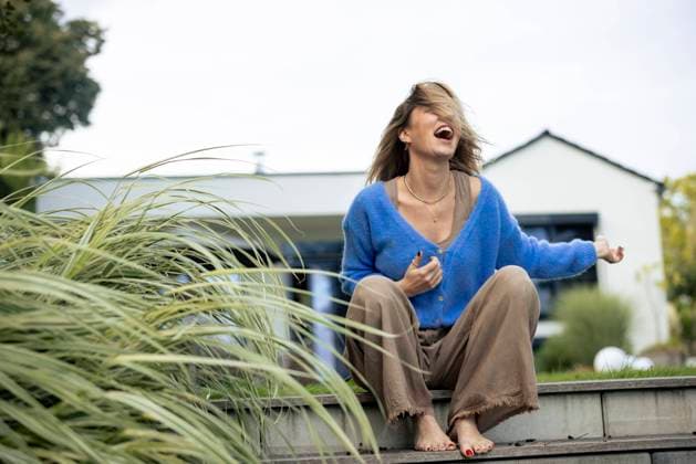 Creative Highlights Symbolbilder Cheerful woman sitting in front of house model released, Symbolfoto property released, JOSEF23238