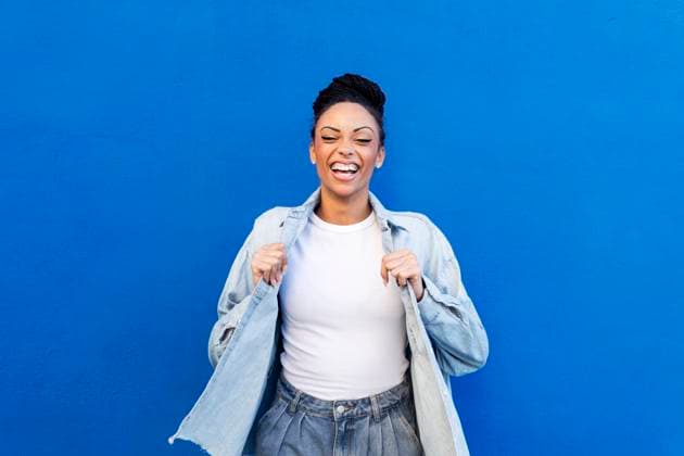 Creative Highlights Symbolbilder Happy woman standing in front of blue wall model released, Symbolfoto, LMCF00911