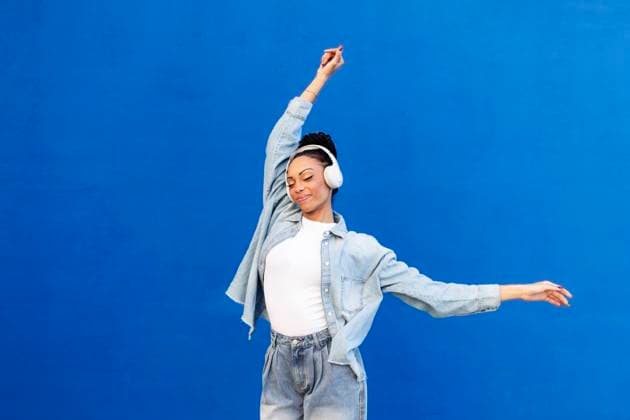 Smiling young woman dancing and listening to music with wireless headphones model released, Symbolfoto, LMCF00920