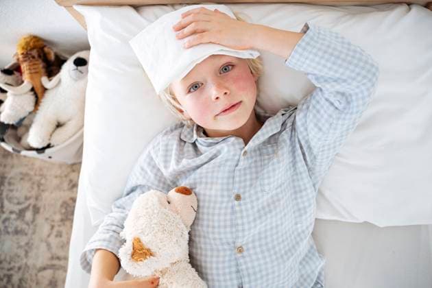 Creative Highlights Symbolbilder Sick boy lying down on bed with compress over forehead at home model released, Symbolfoto property released, NJAF00767