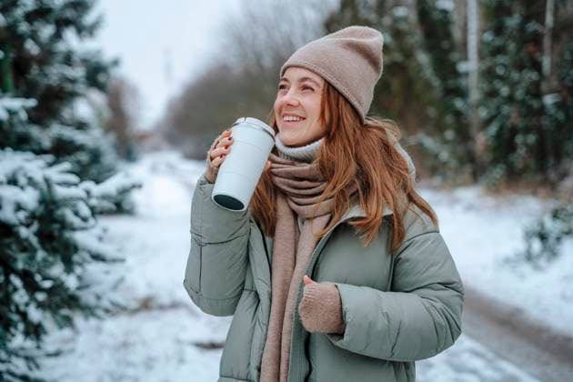 Happy woman holding thermos at footpath in winter model released, Symbolfoto, NLAF00244