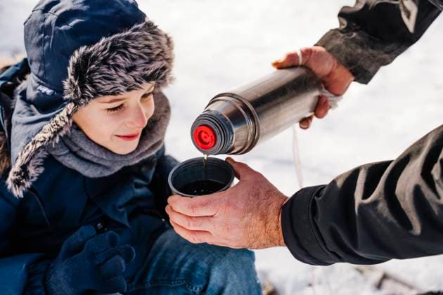 Father pouring hot tea in cup for son in winter model released, Symbolfoto, NLAF00288