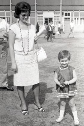 26.07.1964, Dresden, Bezirk Dresden, DDR - Kleines Maedchen schaut laechelnd zum Betrachter. Galopprennbahn Dresden-Seidnitz. (30-40 Jahre, aussen, Aussenaufnahme, Bezirk Dresden, bis 10 Jahre, Blick in die Kamera, Blickkontakt, DDR, deutsch, Deutsche Demokratische Republik, Deutschland, Dresden, Elternteil, Europa, europaeisch, Frau, froehlich, Froehlichkeit, GDR, HF, Historie, historisch, Hochformat, Jahreszeit, Kamerablick, Kaukasierin, kaukasisch, Kind, Kindheit, Kleid, Kleinkind, laecheln, laechelnd, Maedchen, Menschen, Mutter, Personen, s w, schwarz-weiss, Sommer, Westeuropa) 640726A005DRESDEN.JPG *** 26 07 1964, Dresden, district Dresden, GDR Little girl looks smiling to the viewer racecourse Dresden Seidnitz 30 40 years, outside, o