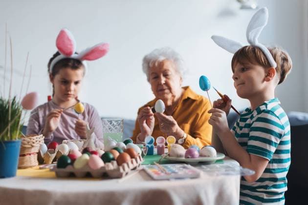 Grandmother with little kids decorating easter eggs at home. Tradition of painting eggs with brush and easter egg dye. Grandmother with little kids decorating easter eggs at home. Tradition of painting eggs with brush and easter egg dye. Concept of family easter holidays. model released