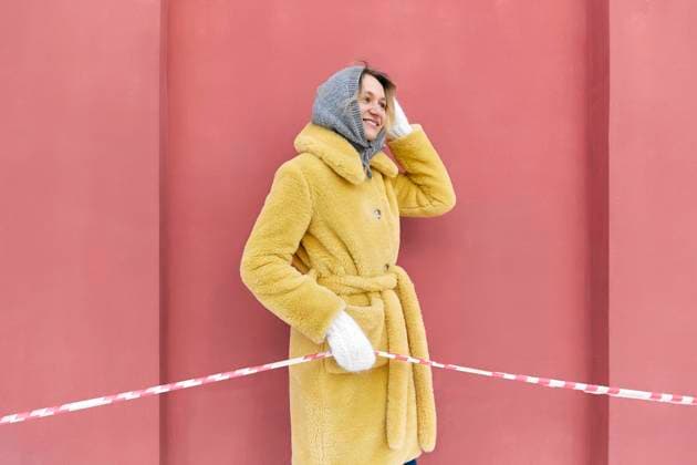 Creative Highlights Symbolbilder Happy young woman holding red and white barricade tape in front of peach wall model released, Symbolfoto, SANF00171