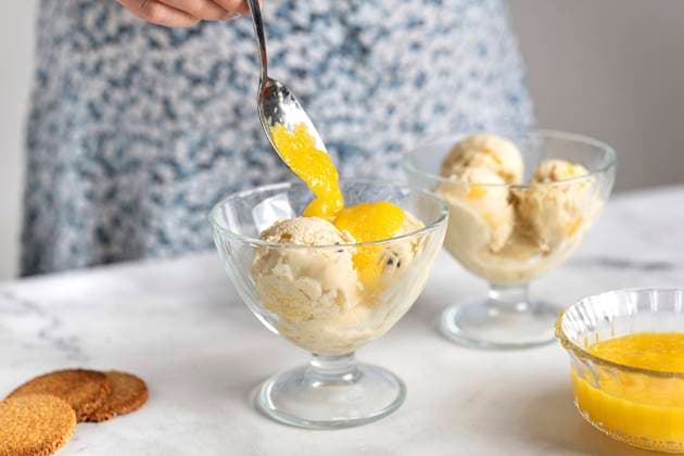 Woman putting fruit sauce on ice cream in bowl model released, Symbolfoto, TILF00070
