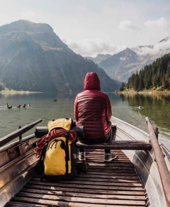 Creative Highlights Symbolbilder Young woman with backpack sitting in boat at lake Vilsalpsee near mountains, Tyrol, Austria model released, Symbolfoto, UUF31087