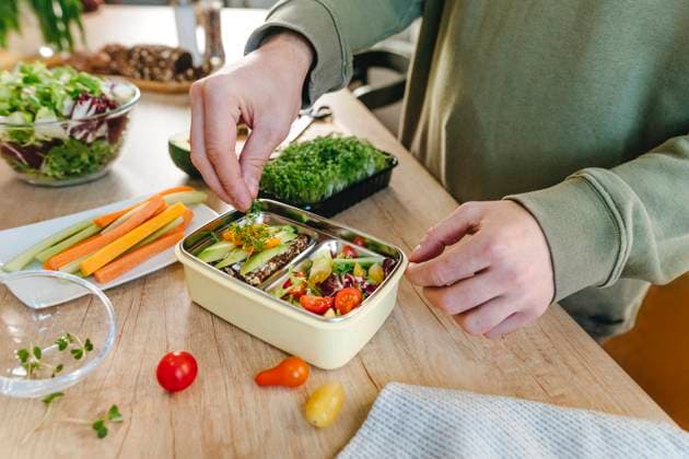 IMAGO Creative, Food, Trend, Meal Prep Man garnishing microgreen over vegetarian food in lunch box model released, Symbolfoto property released, YTF01683