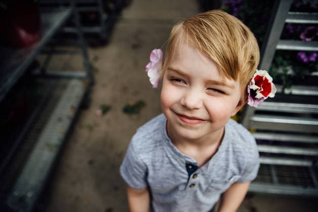 Creative Highlights Symbolbilder Portrait of young boy smiling with flowers tucked behind his ears. Bismarck, North Dakota, United States CR_KIFR240228-1358274-01 ,model released, Symbolfoto