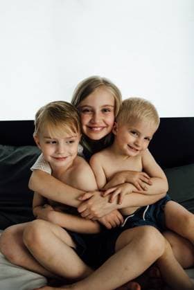 Three siblings hug and smile at camera at home. Bismarck, North Dakota, United States CR_KIFR240228-1358281-01 ,model released, Symbolfoto