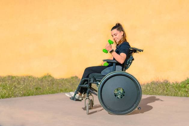 Creative Highlights Symbolbilder MR_ID19661_16408_GemaGarzon.jpg, PR_ID19661_6551_TattoosGema.jpg Woman in a wheelchair lifting a green dumbbell for a bicep curl, engaging in strength training outdoors, Property released Model Released NataliaPenado_ID19661_582995_008 Copyright: xNataliaxPenadox RECORD DATE NOT STATED