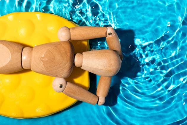 Wooden artist s mannequin relaxing on a yellow pool float in clear blue swimming pool water, simulating a summer leisure scene Model Released SergioVictorVega_ID19896_589862_003 Copyright: xSergioxVictorxVegax