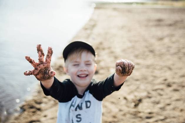 Creative Highlights Symbolbilder Young boy laughing and holding up his sandy hands at a beach. Bismarck, North Dakota, United States R_KIFR240228-1358340-01 ,model released, Symbolfoto