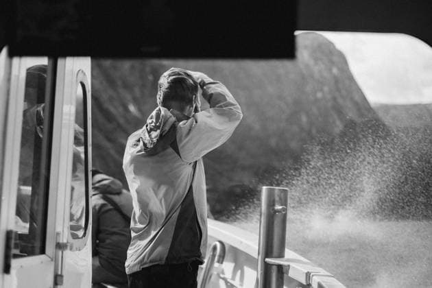 Creative Highlights Symbolbilder Tourist man takes picture on windy boat tour in Milford Sound Milford Sound, Southland, New Zealand R_UTNS240301C-1319400-01 ,model released, Symbolfoto
