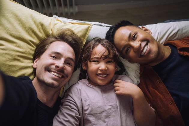 Directly above portrait of happy gay couple lying down with daughter at home Sweden, Stockholm, model released, property released Copyright: xMaskotx , MA107583 MA107583