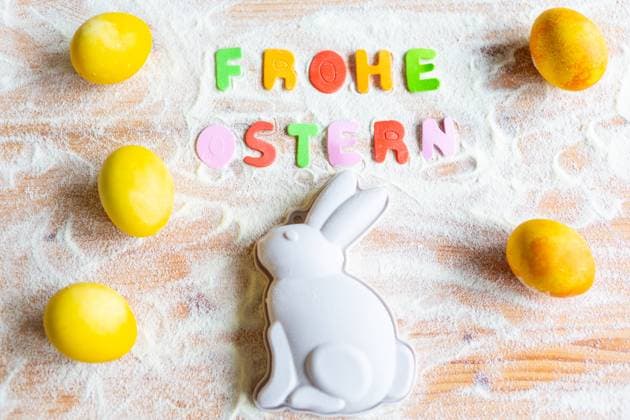 3 March 2024: Baking at Easter concept, Easter bunny baking tin on a worktop with flour and Easter eggs with text lettering: Happy Easter *** Backen an Ostern Konzept, Osterhasen Backform auf einer Arbeitsplatte mit Mehl und Ostereiern mit Text Schriftzug: Frohe Ostern