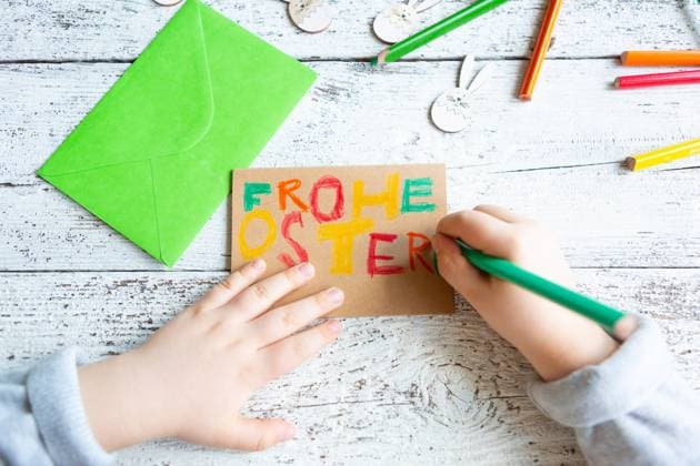 3 March 2024: Child making Easter decorations, hand writing with colored pencils: Happy Easter *** Kind beim Basteln von Osterdekoration, Hand schreibt mit Buntstiften: Frohe Ostern