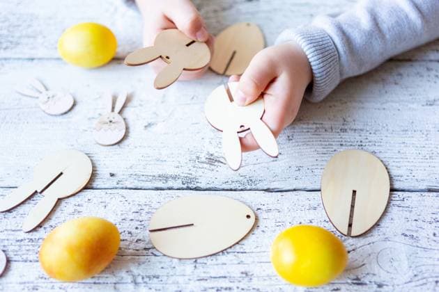 3 March 2024: Little boy making Easter decorations. Hand of child assembling wooden parts of an Easter bunny *** Kleiner Junge beim Basteln von Osterdekoration. Hand von Kind baut teile aus Holz von einem Osterhasen zusammen