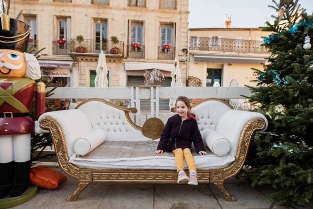Creative Highlights Symbolbilder Little girl sits on decorated Christmas couch at December market Béziers, Occitanie, France CR_JIBA240309-1366193-01 ,model released, Symbolfoto