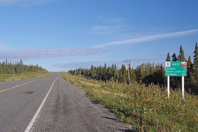 Straße führt als endlose Grade durch Wildnis, kein Verkehr und ein Verkehrschild, Alaska Highway, Yukon Territory, Kanada, Nordamerika