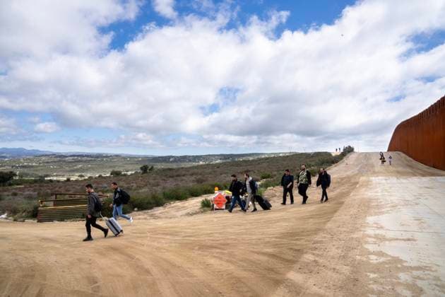 Migrants walk down the border road to surrender to the U.S. Border Patrol after crossing the border wall from Mexico near Campo, California, about 50 miles from San Diego, on Wednesday, March 13, 2024. A bipartisan Senate immigration bill to address the migrant immigration issue is stalled in the House due to election year politics.  CAL2024031405 PATxBENIC